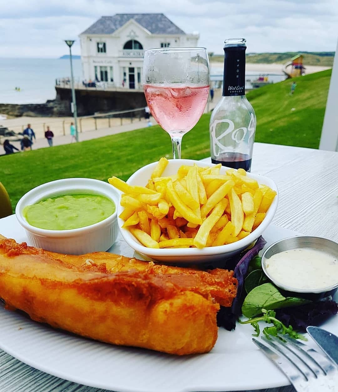 a plate of food with a glass of wine and a house in the background